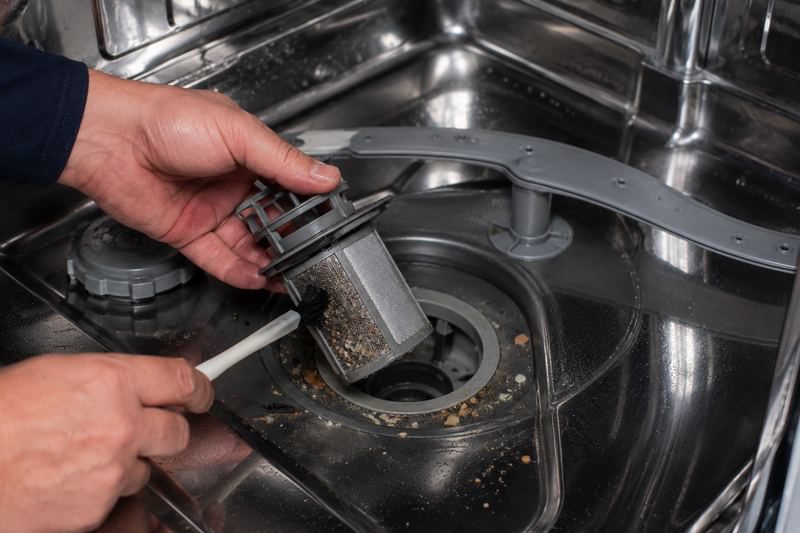 APA Appliance Repair technician cleaning a dishwasher filter in a Bay Area home